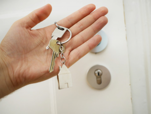 hand holding house keys in front of white door
