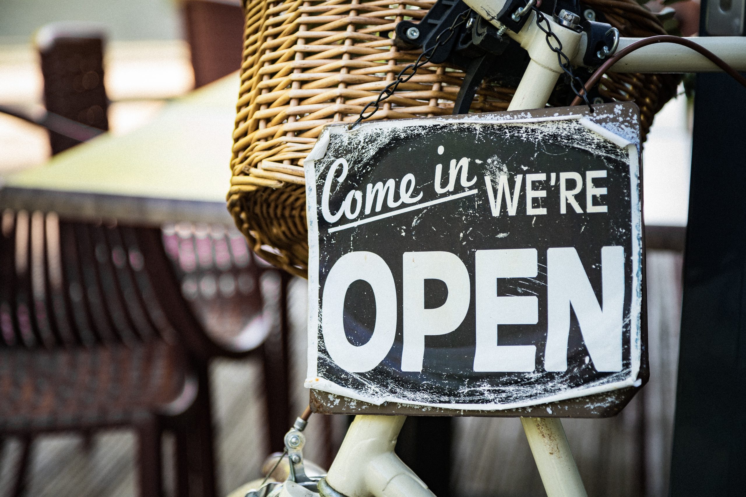 Black and white 'we're open' sign on a wicker bicycle basket