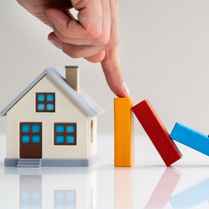 image of hand protecting little house from toppling dominoes to demonstrate interest rate buffer