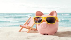 image of a piggy bank in yellow sunglasses next to a small beach chair on the beach