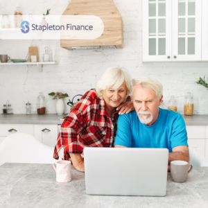 older couple looking at a laptop at their kitchen benchtop with kitchen cupboards and appliances behind them for home loans for older borrowers 