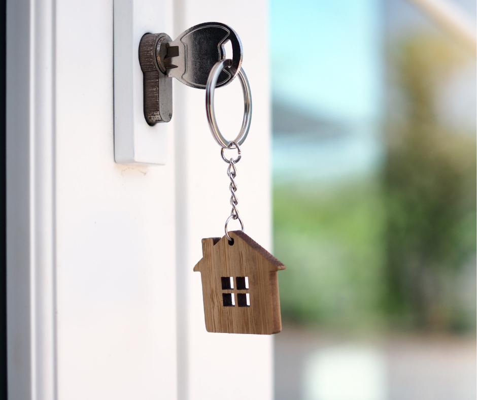 key in a lock of the door with a small brown house as a keychain for home finance journey