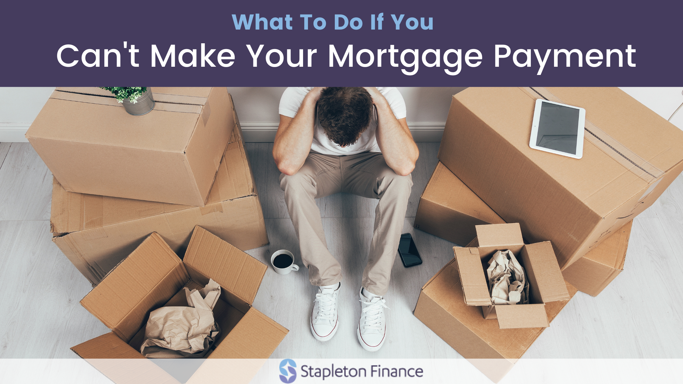 man sitting on the floor in white shirt and khakis holding his head in his hands surrounded by packing boxes for what to do if you can't make your mortgage payment