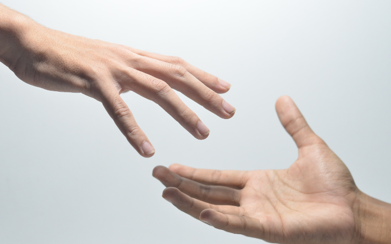 graphic of two male hands reaching out for each other against a grey background for reaching out to your lender when what to do if you can't make your mortgage payment