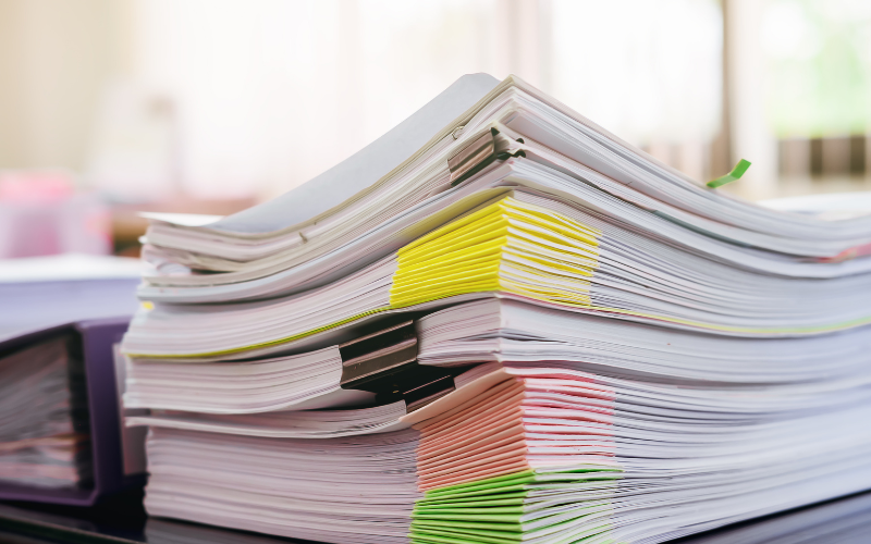 stack of documents with tabs and elephant clips stacked up on a desk for gather your documents for what to do if you can't make your mortgage payment