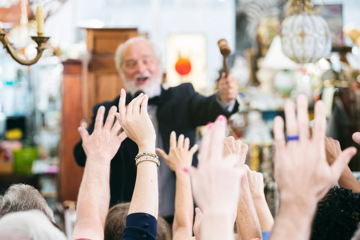 image of hands reaching into the air with fingers pointing up for home finance for auction with grey haired auctioneer