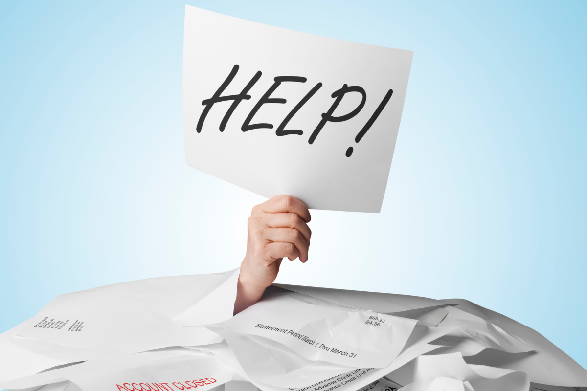 image of person buried in paperwork with just just the hand sticking up holding a sign that says help for goal setting financial