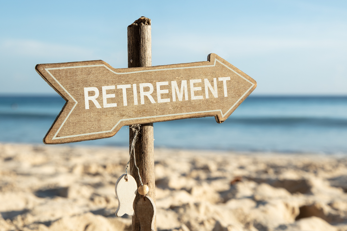 wooden arrow pointing towards the ocean and sand with the word retirement written on it