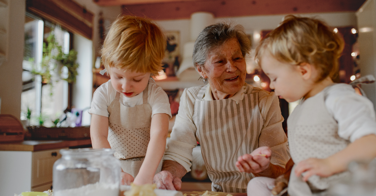grandmother cooking with her grandchildren in a striped apron.